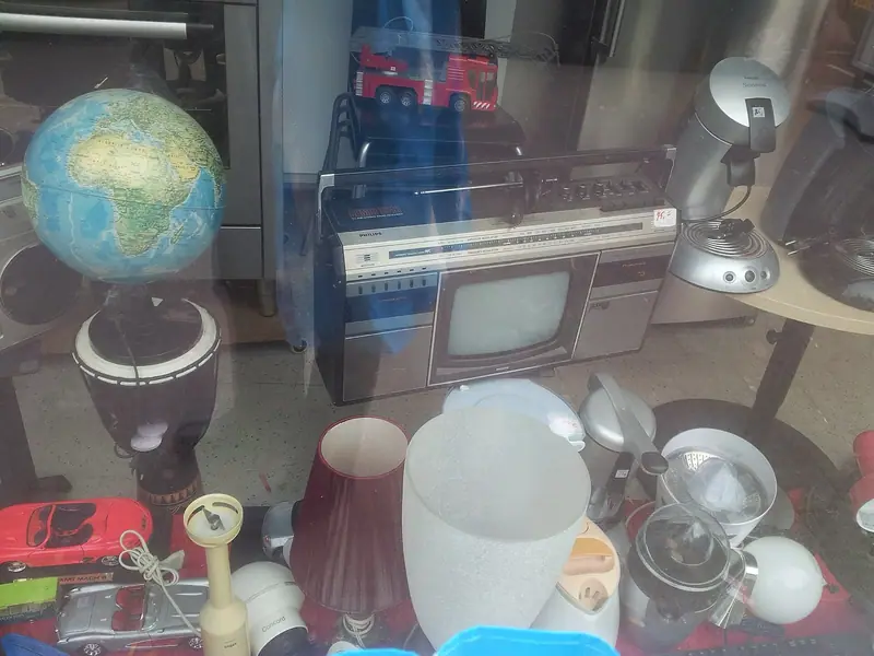 Vitrine de brechó holandês com globo, rádio antigo e objetos usados